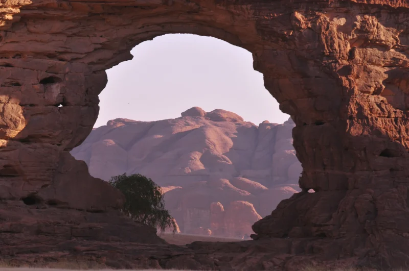 Breathtaking view of the "Eye of Tokou" natural arch, a unique geological phenomenon in the Ennedi plateau, with an impressive landscape in the background.