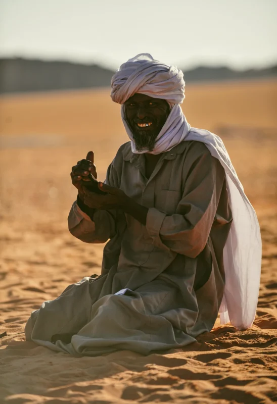Un homme touareg sourit, incarnant l'hospitalité et la chaleur humaine du désert.